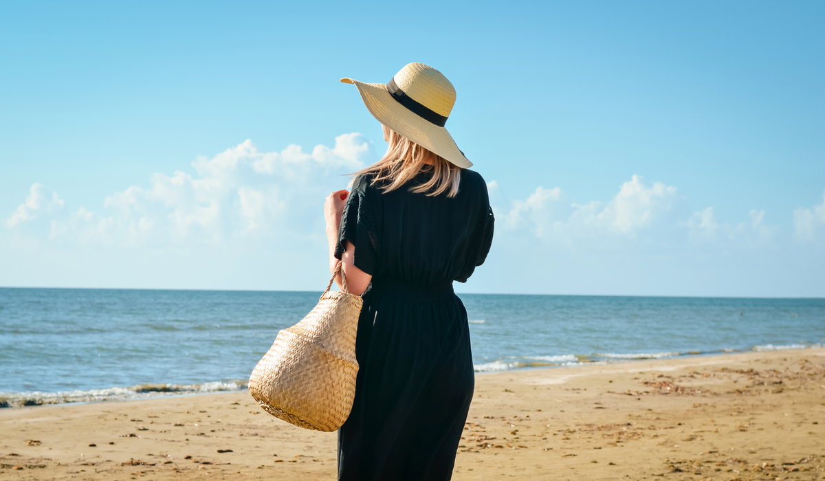 Frau in schwarzem Kleid am Strand