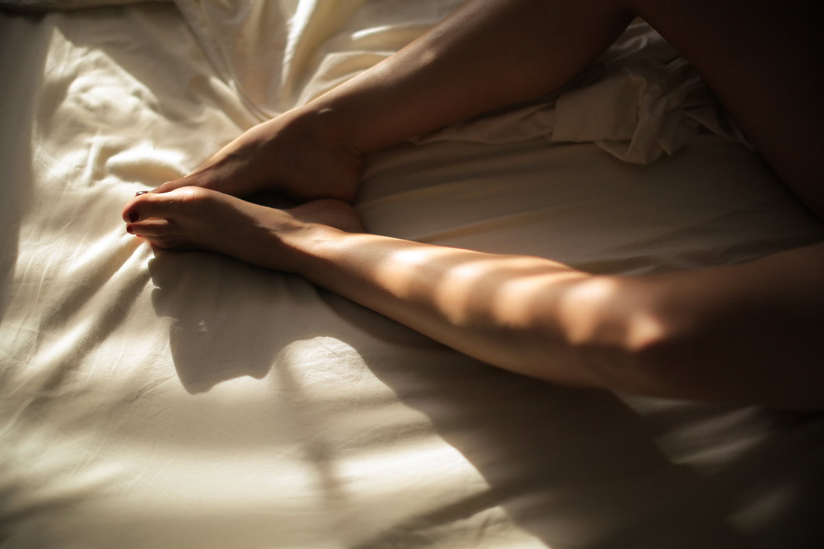 Beine einer Frau im Bett