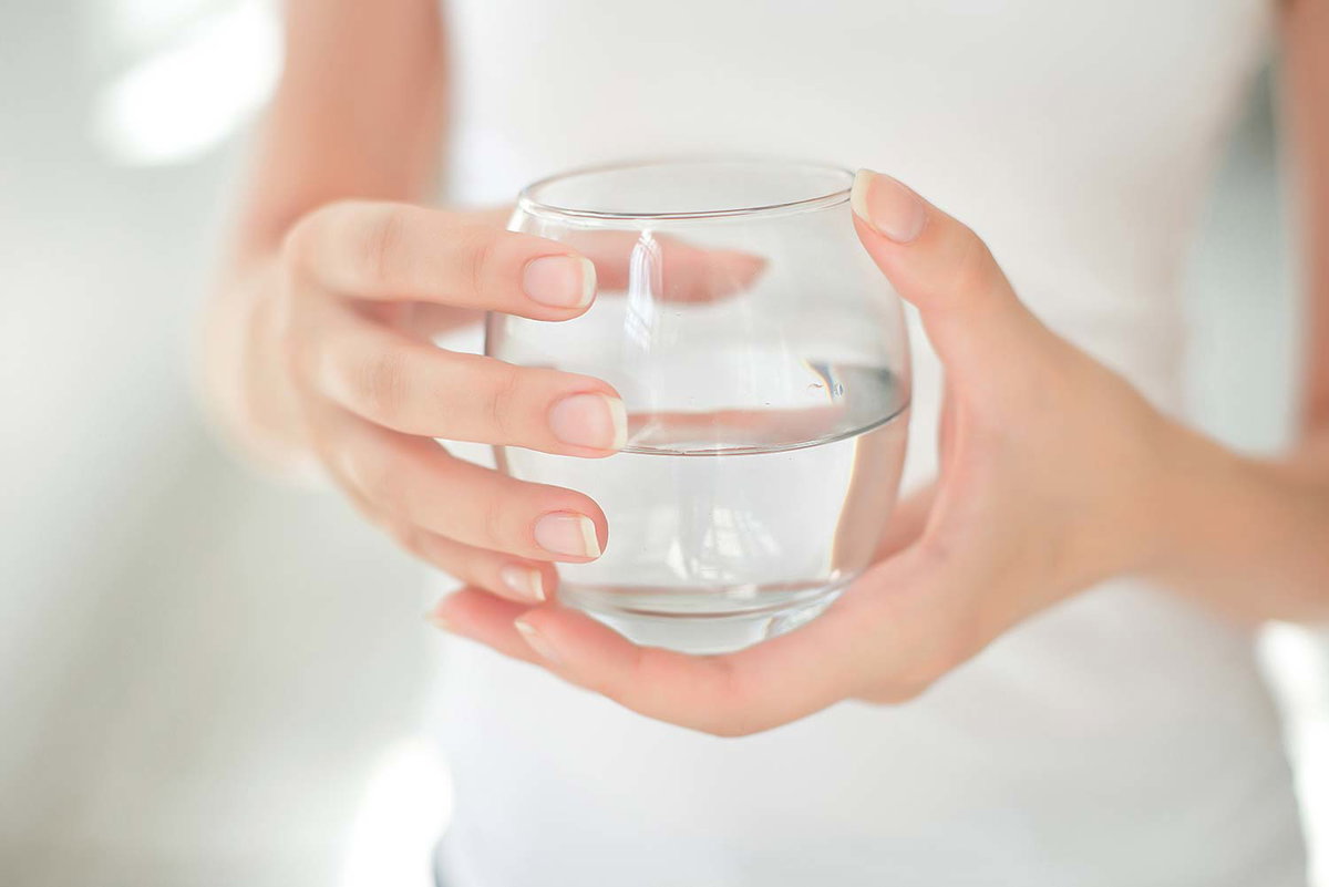 Viel trinken ist gesund: Frau hält ein Glas mit Wasser