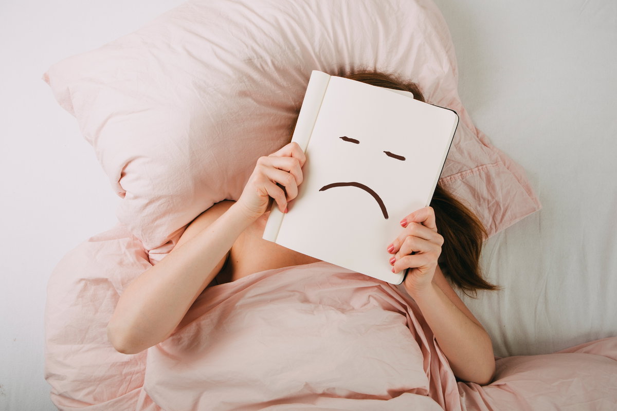 Frau liegt im Bett und schmollt