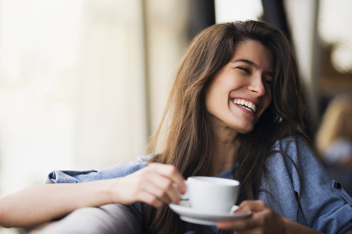 Lächelnde Frau mit Kaffeetasse in der Hand