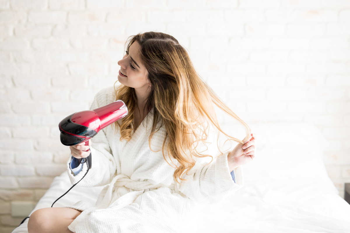 Frau föhnt sich die Haare