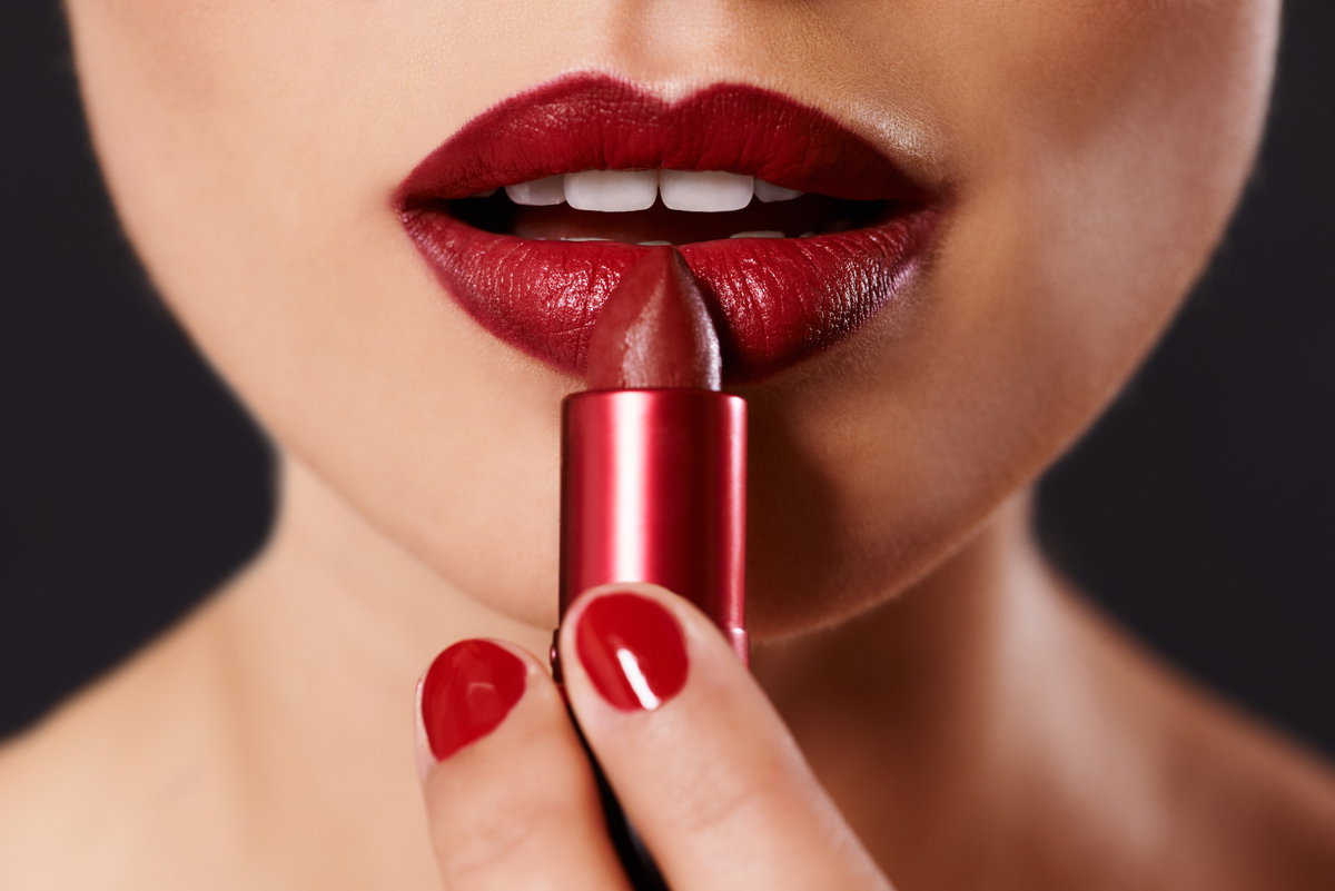 Junge Frau trägt roten Lippenstift auf