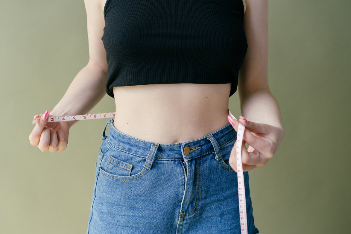 schlanke Frau misst Bauch mit Maßband