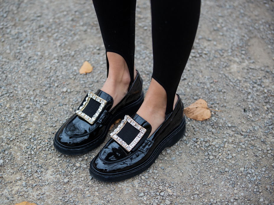 Frau trägt schwarze Loafer mit großer Schnalle.