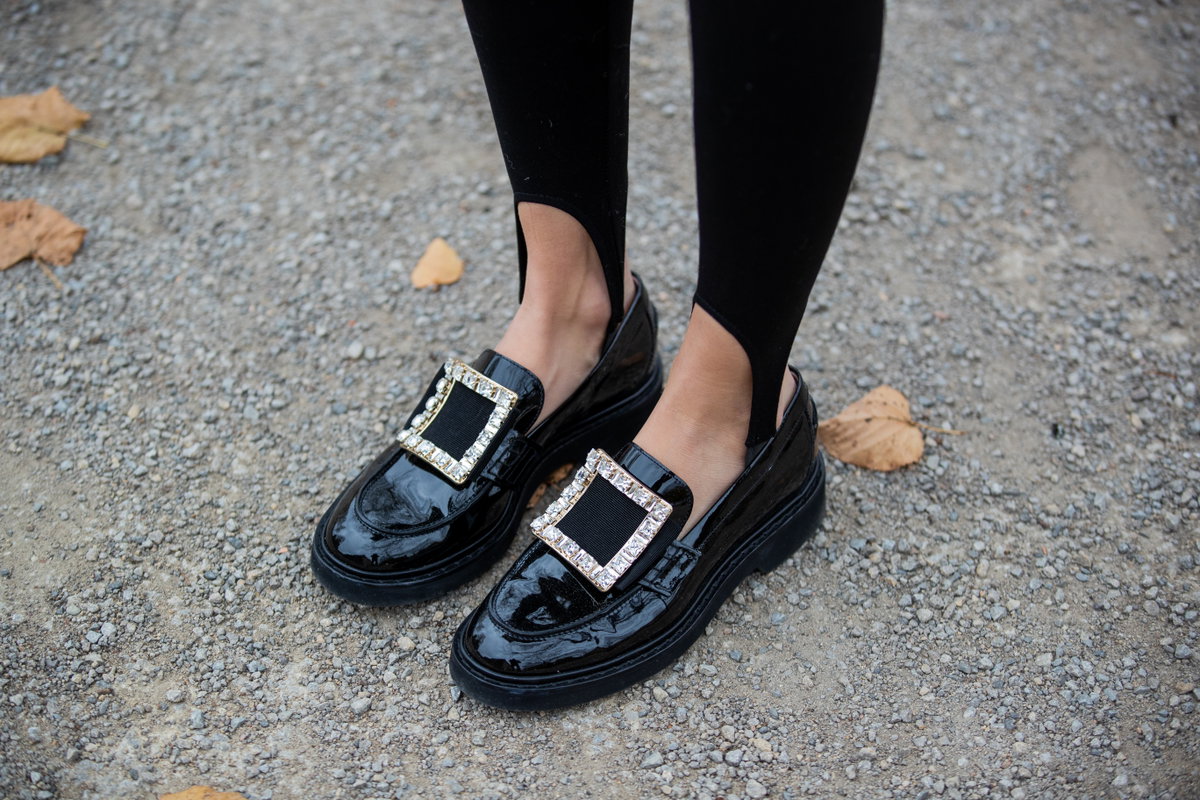 Frau trägt schwarze Loafer mit großer Schnalle.
