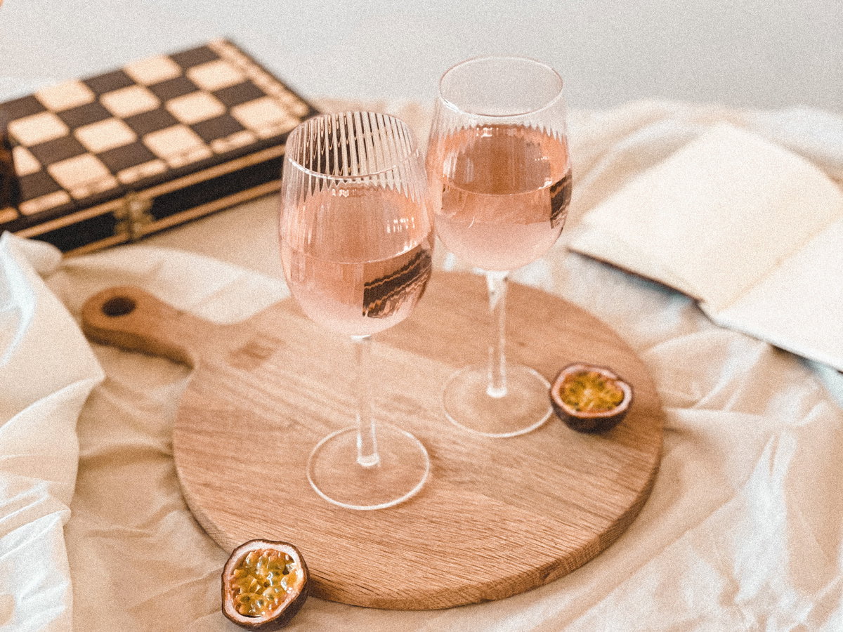 Zwei Gläser Rosé stehen auf einem Holzbrett.