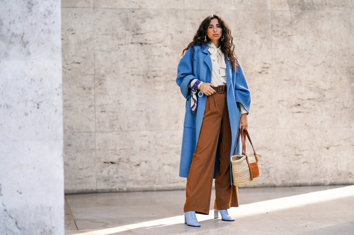 Frau in weiter Hose und blauem Mantel