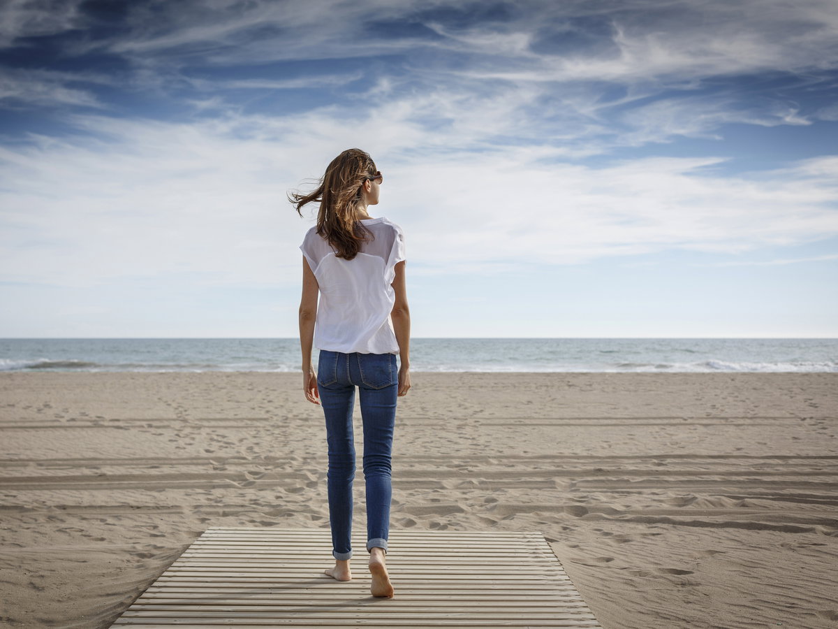 Frau beim Rückwärtsgehen am Meer