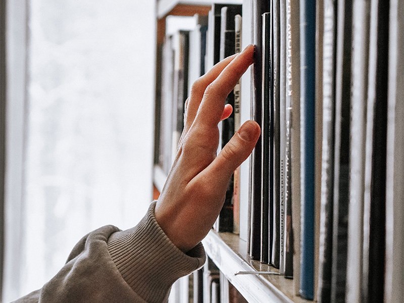 Finger, der über Bücher bewegt wird
