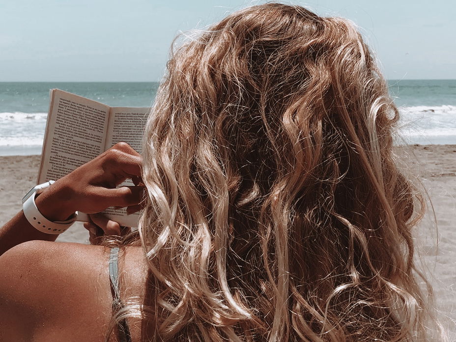 Frau liest am Strand ein Buch