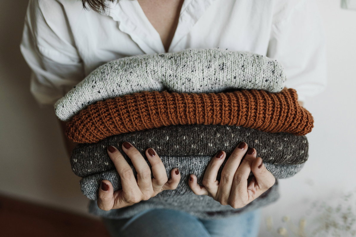 Frau mit einem Stapel Wollpullover