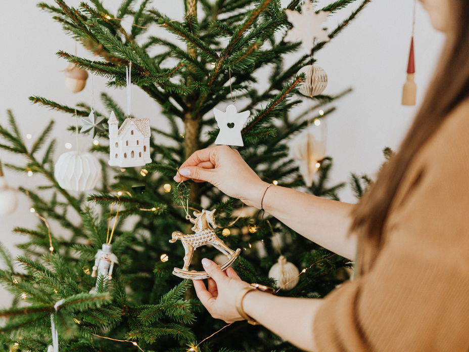 Frau schmückt Weihnachtsbaum mit Christbaumschmuck