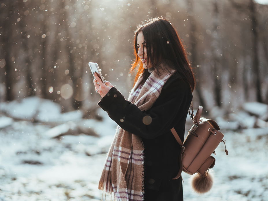 Frau hält Smartphone im Winter