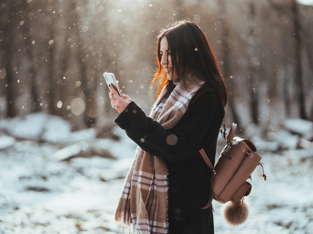 Frau hält Smartphone im Winter