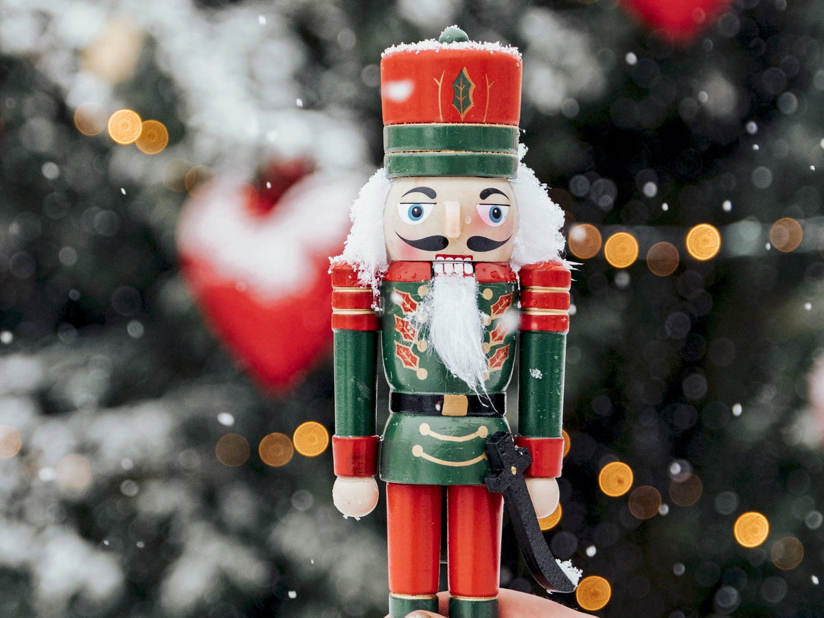 Frau hält einen Nussknacker vor winterlichen Hintergrund.