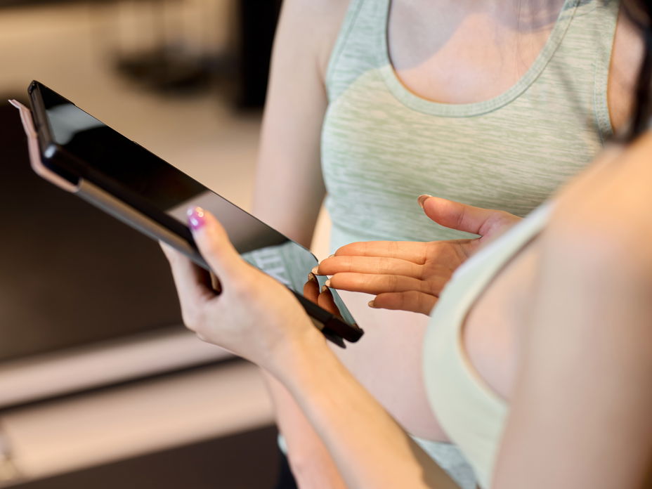 Frau zeigt kostenlose Trainingspläne auf dem Tablet