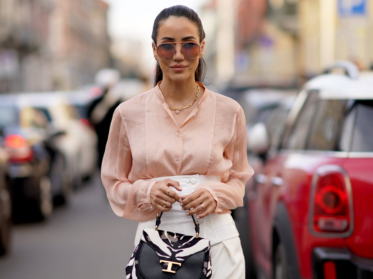 Frau im eleganten Streetstyle mit einer Bluse in der Farbe Peach Fuzz.
