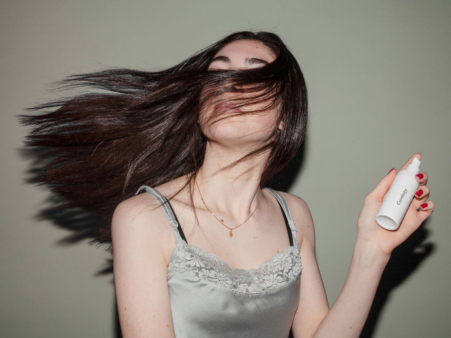 Frau hält pflegendes Haarspray