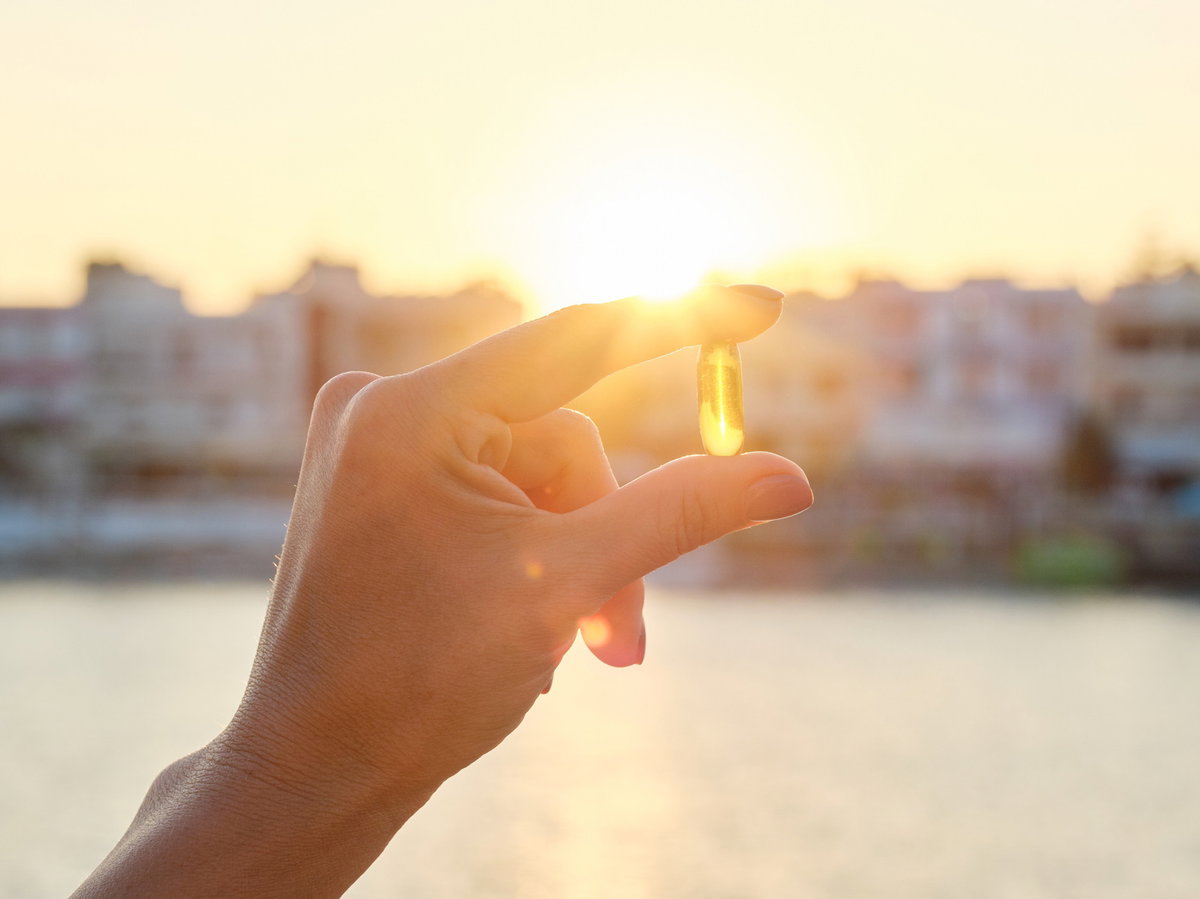 Vitamin D Kapsel zwischen den Fingern