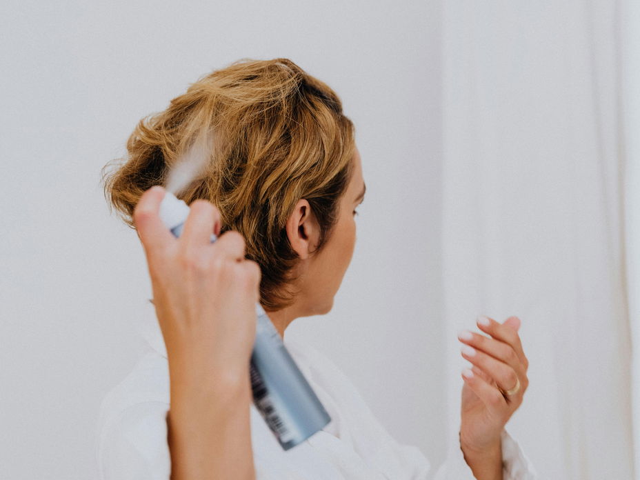 Frau sprüht Haarspray