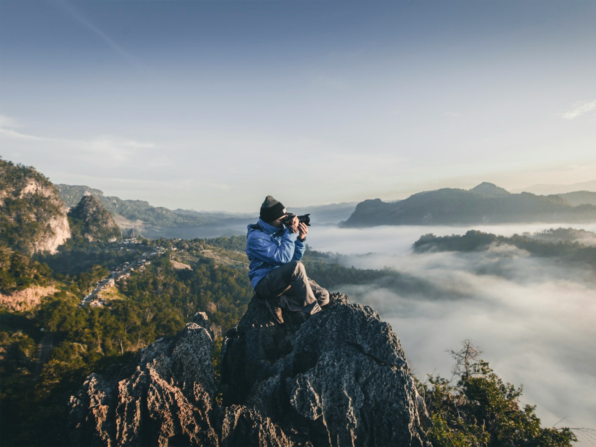 Mann fotografiert die Landschaft auf einem Berg