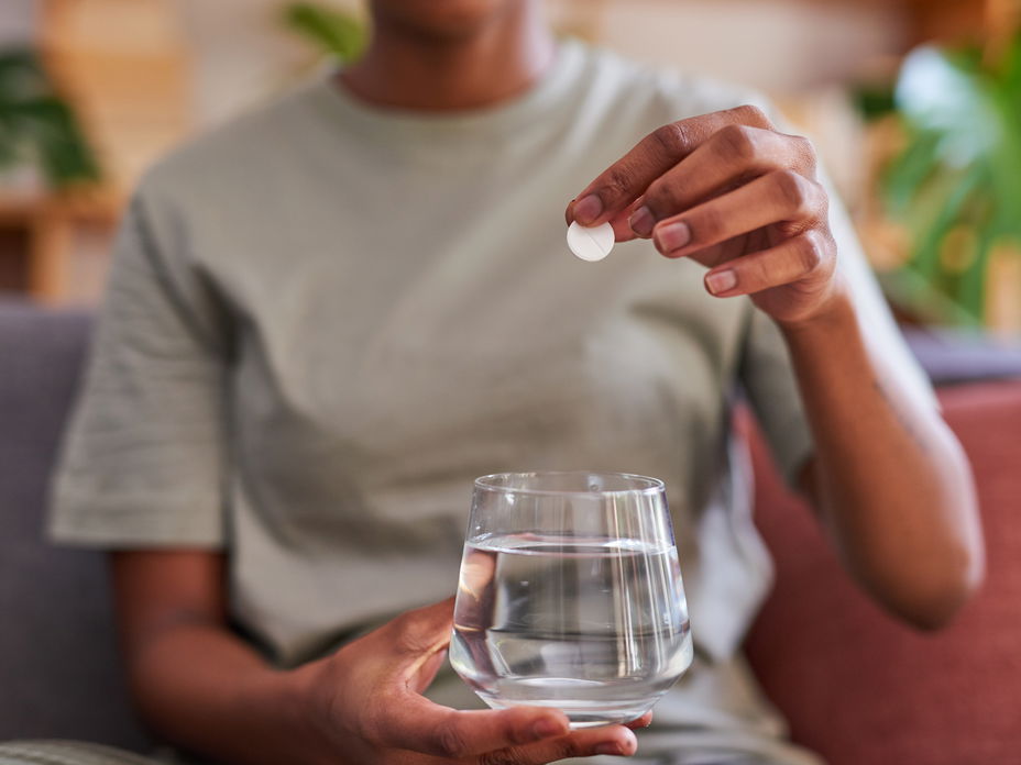 Frau wirft Brausetablette in ein Glas Wasser