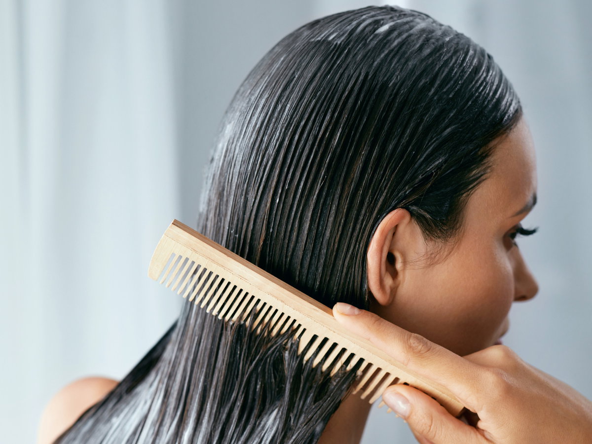 Frau kämmt Haarpflegeprodukt ein