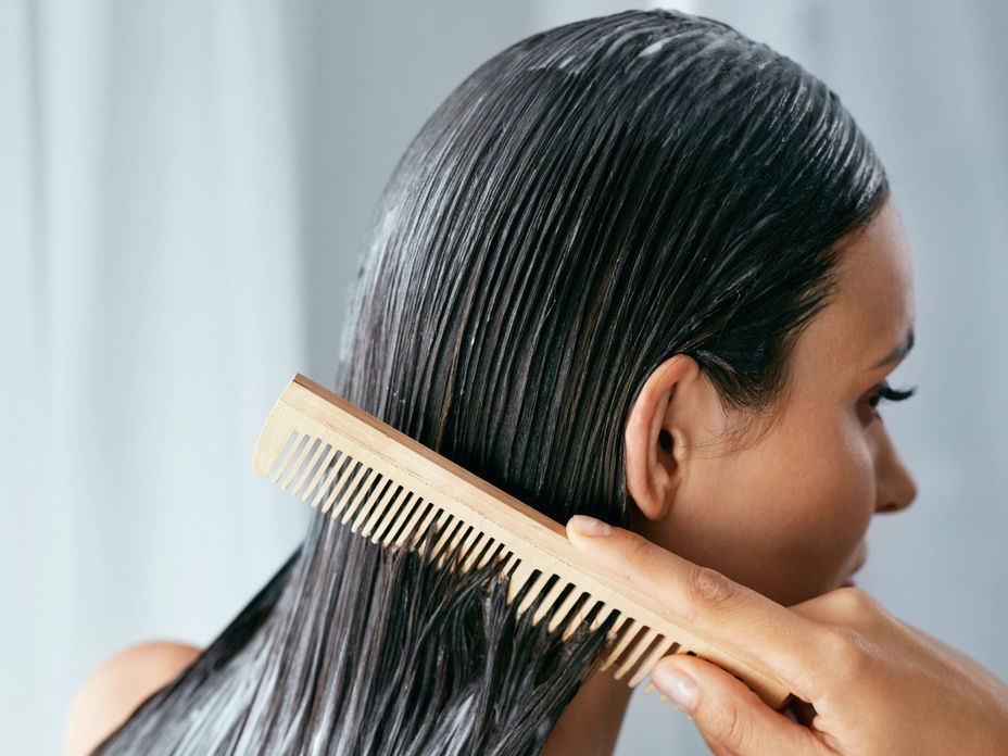 Frau kämmt Haarpflegeprodukt ein