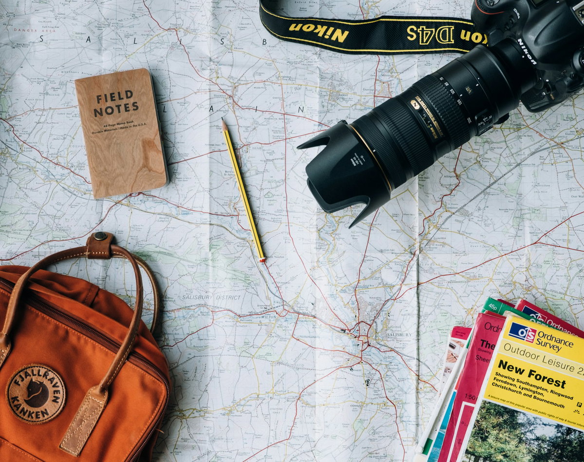 Landkarte mit Kamera, Rucksack, Bleistift und Reiseführern