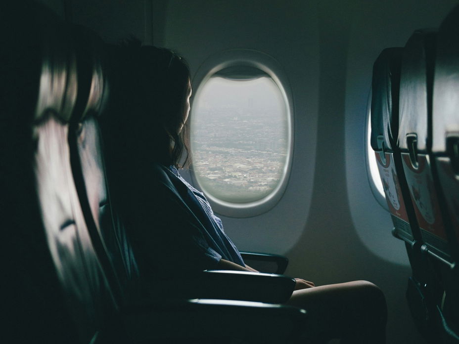 Frau sitzt im Flugzeug am Fenster.