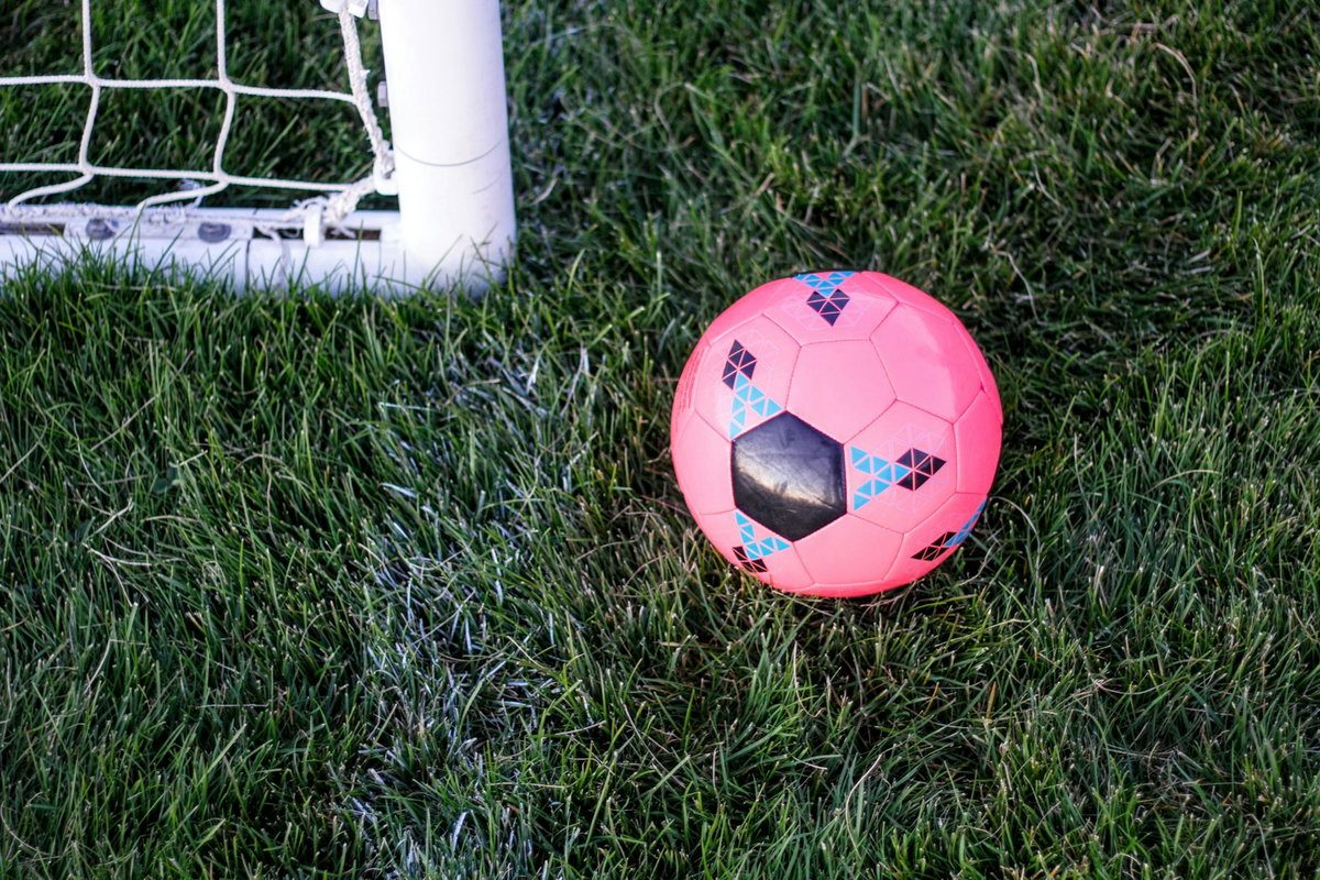 Pinker Fußball auf dem Rasen neben einem Tor
