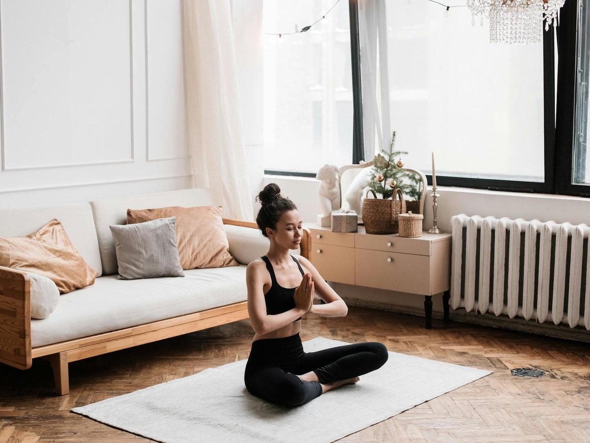 Frau sitzt auf dem Boden und macht eine Yoga Pose