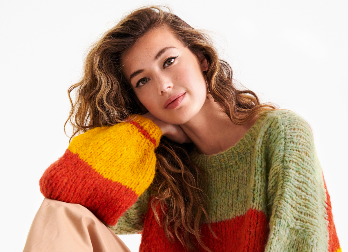 Model in selbst gestricktem Regenbogen-Pullover