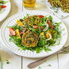 Die veganen Zucchini-Bratlinge werden auf einem Tomaten-Rucola-Salat serviert - und sind Low Carb!