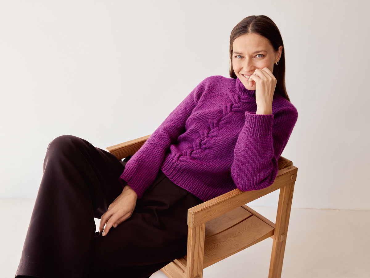 Model in fuchsiafarbenem Zopfmuster-Rollkragenpullover von Lana Grossa