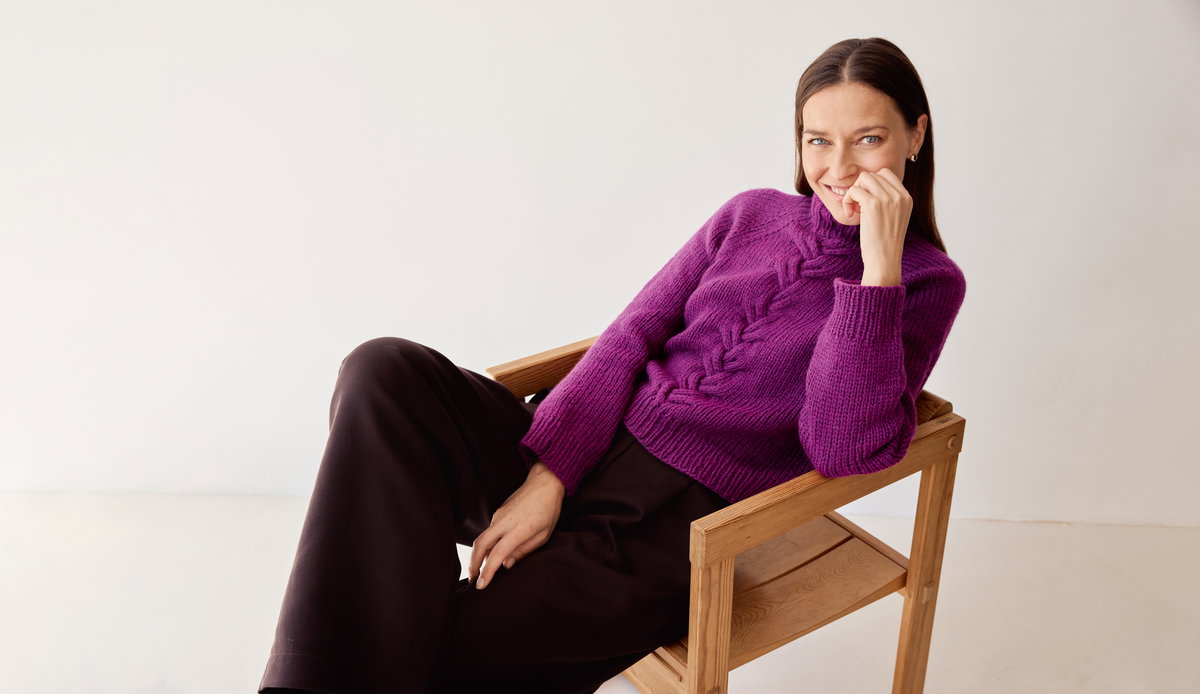 Model in fuchsiafarbenem Zopfmuster-Rollkragenpullover von Lana Grossa