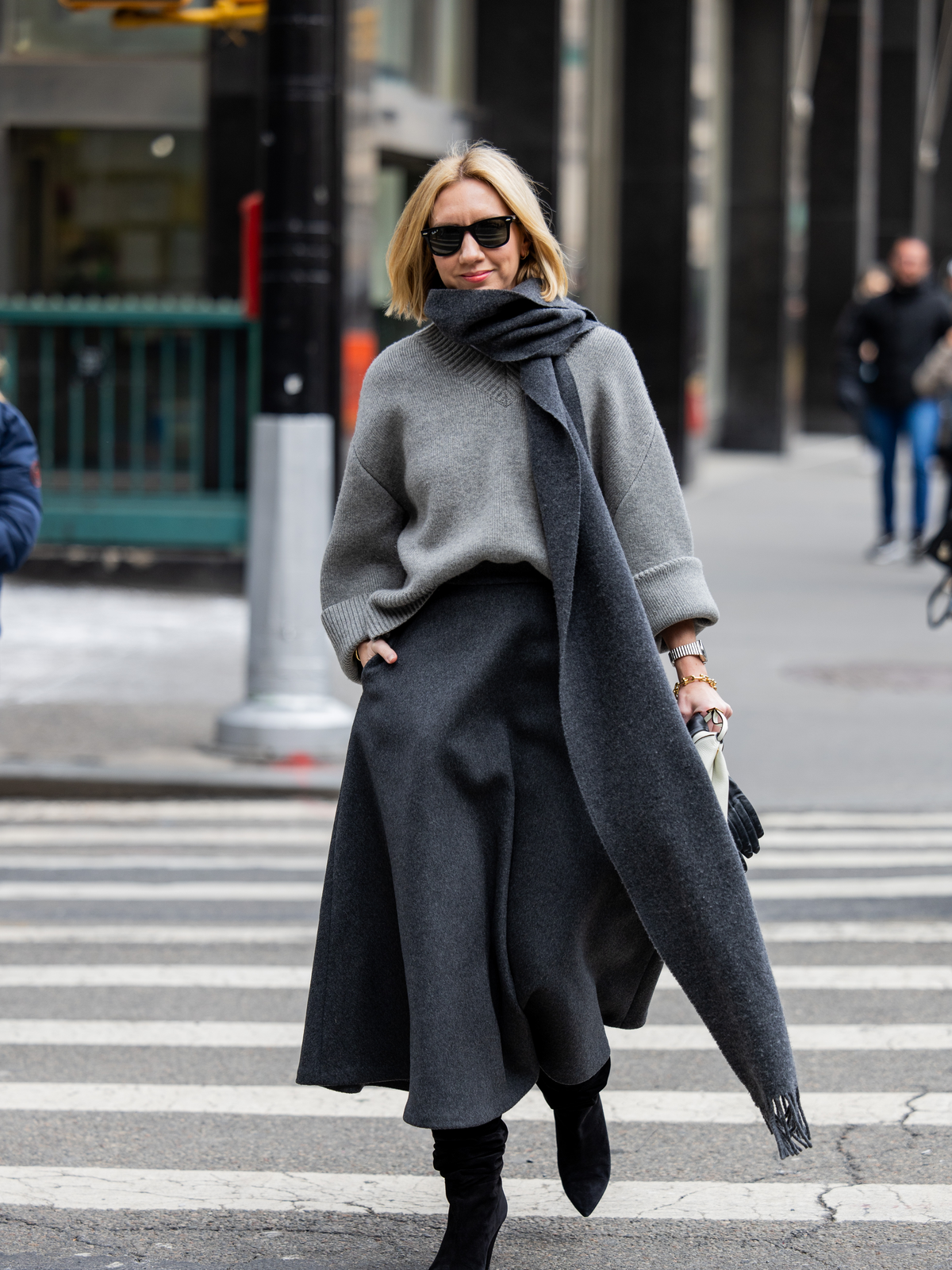Stricktrends 2025 - Lisa Aiken trägt einen grauen V-Pullover