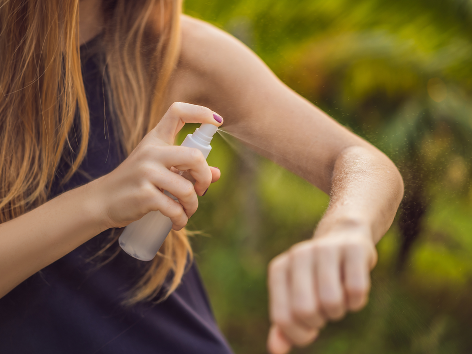 Frau sprüht sich mit selbst gemachtem Zeckenspray ein