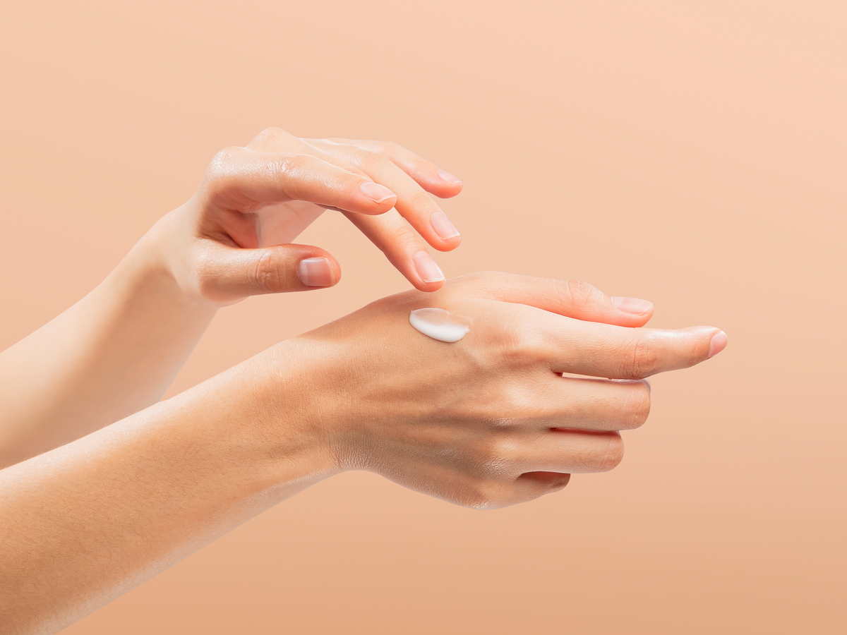Frau trägt Handcreme mit Sonnenschutz auf ihre Hände auf