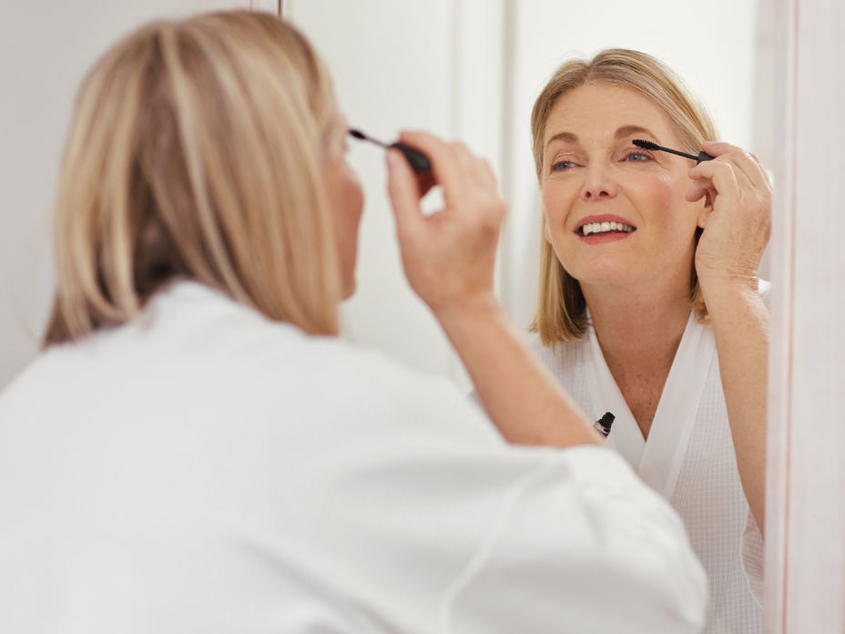 Frau tuscht ihre Wimpern vor Spiegel