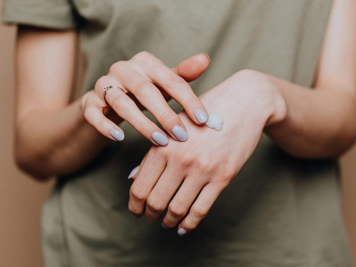 Frau, die Handcreme mit einer Hand auf der anderen verteilt