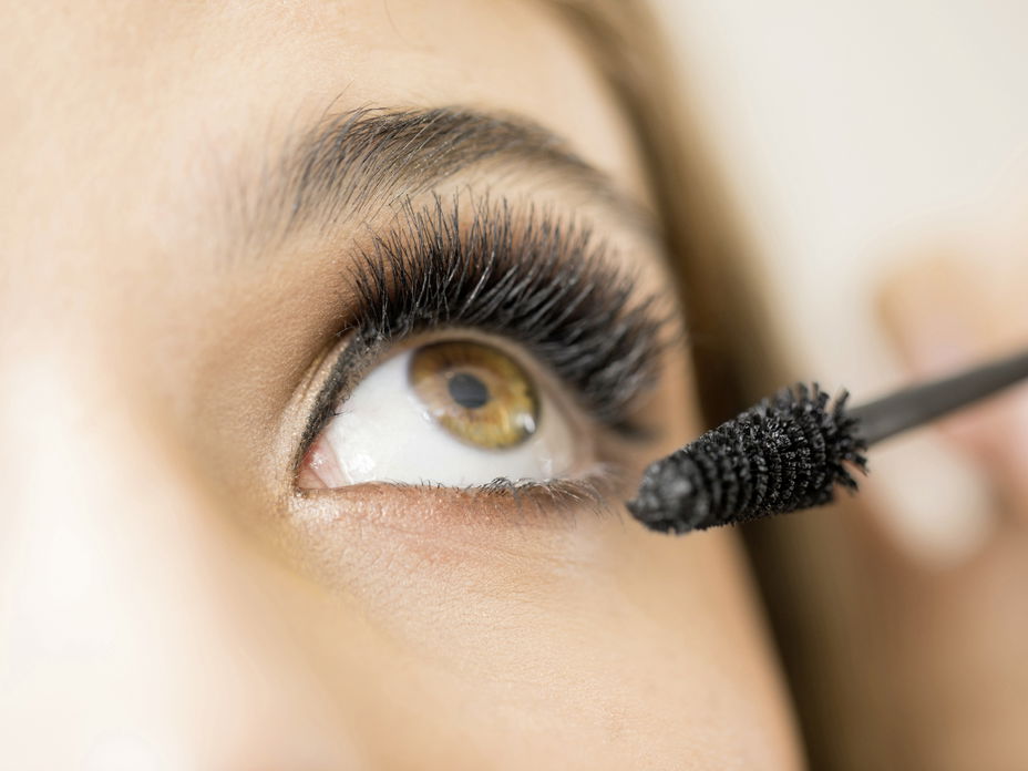 Frau trägt mascara für dichte Wimpern auf