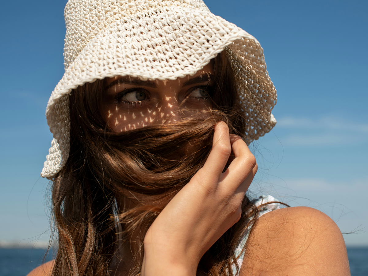 Frau trägt einen Sonnenhut am Strand