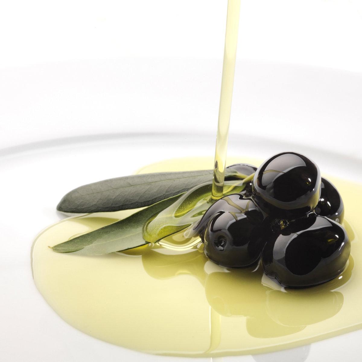 Schwarze Oliven werden mit Olivenöl übergossen - Vielseitig und gesund kochen mit Olivenöl