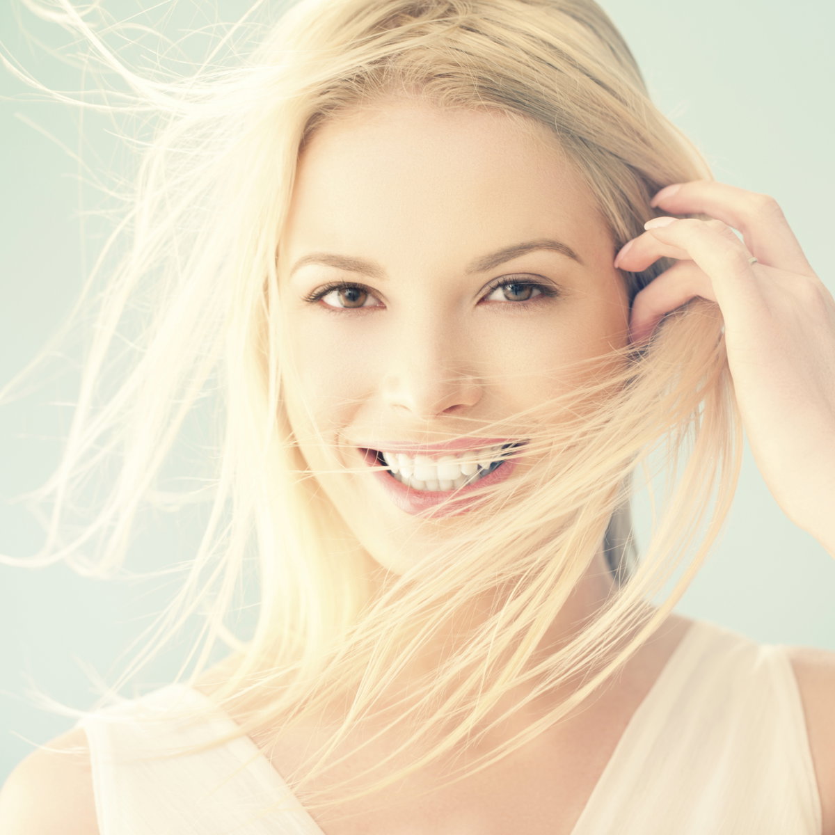 Eine Frau lächelt in die Kamera, ihre blonden Haare wehen im Wind