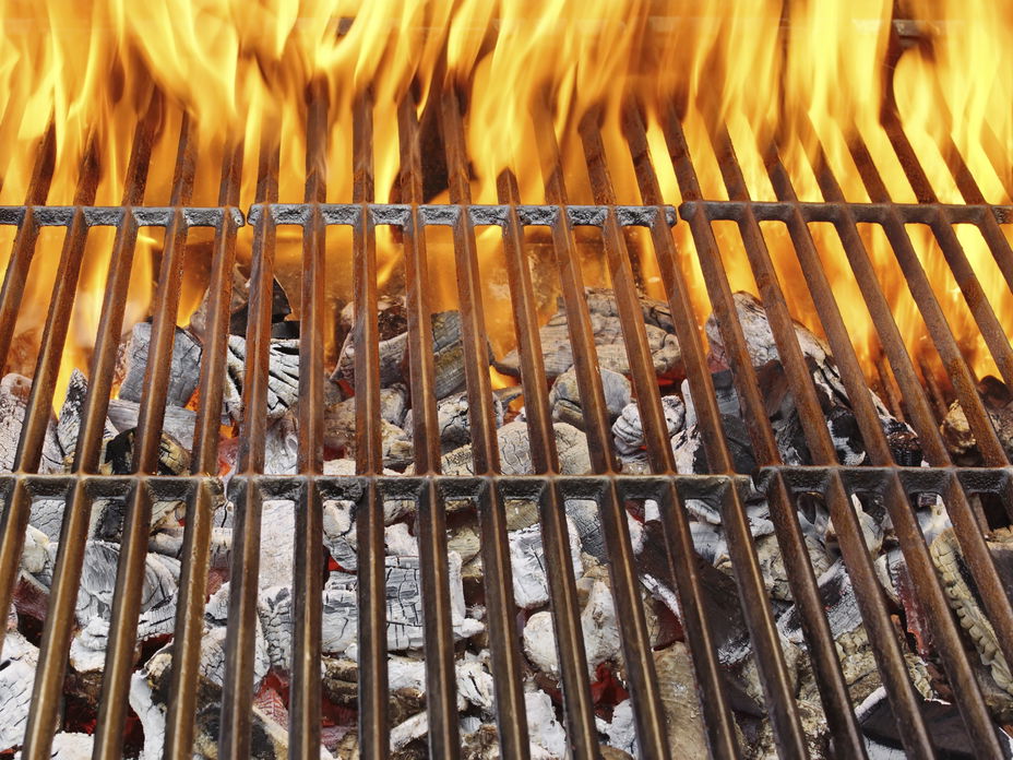 Grillrost mit Feuer - Wir geben Tipps, wie Sie Ihren Grill wieder sauber bekommen – mit wenig Aufwand und Geld