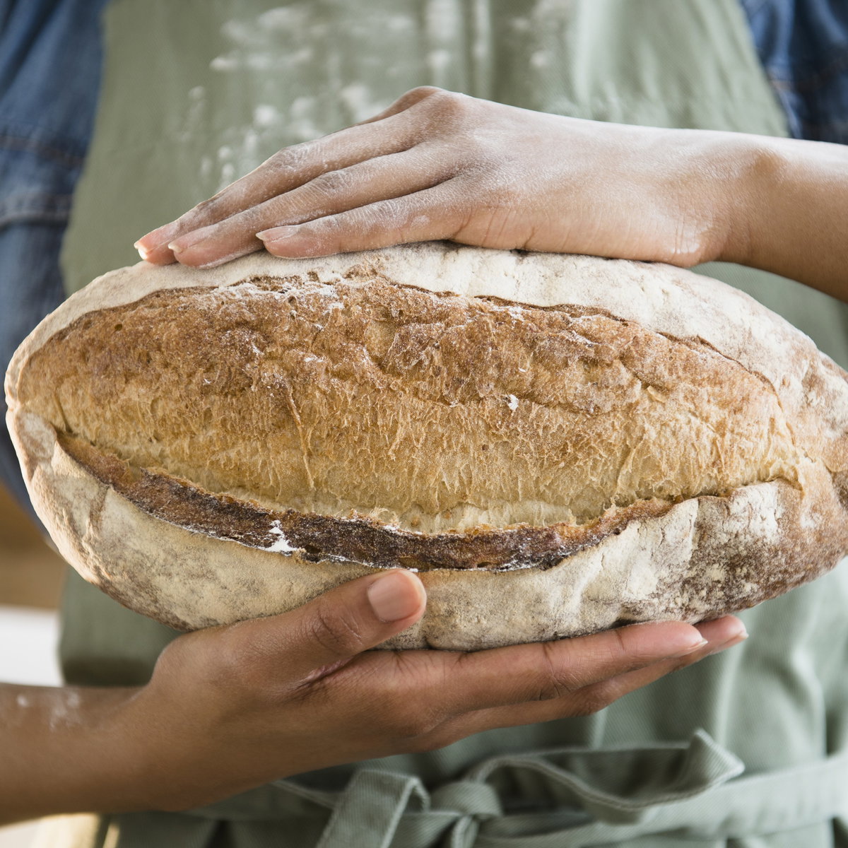 Frau hält selbstgebackenes Roggenbrot in den Händen - Das Backrezept gibt es hier