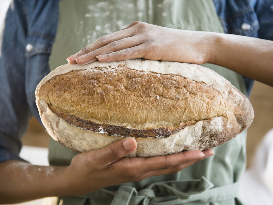 Frau hält selbstgebackenes Roggenbrot in den Händen - Das Backrezept gibt es hier