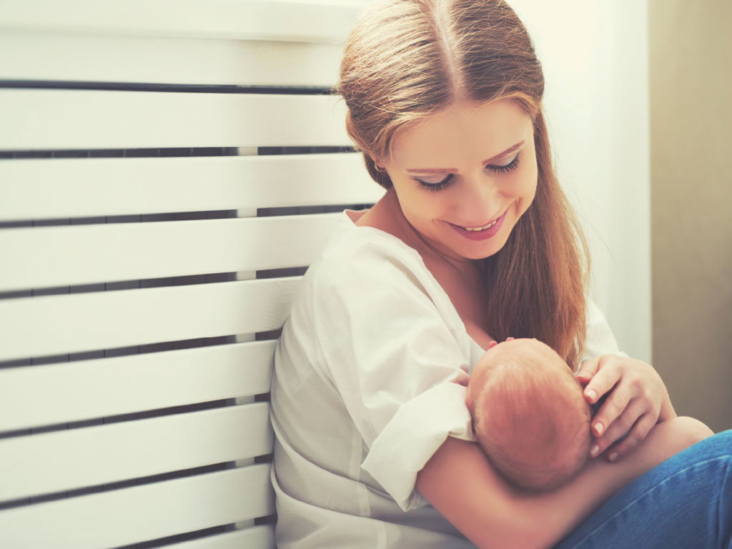 Junge Mutter hält ihr Baby in Fütterposition
